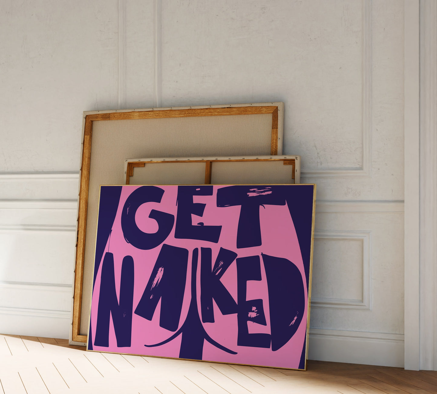 A picture frame leaning against a wall, bold purple pink lettering reading "Get Naked" with a butt cheek drawing at its center.