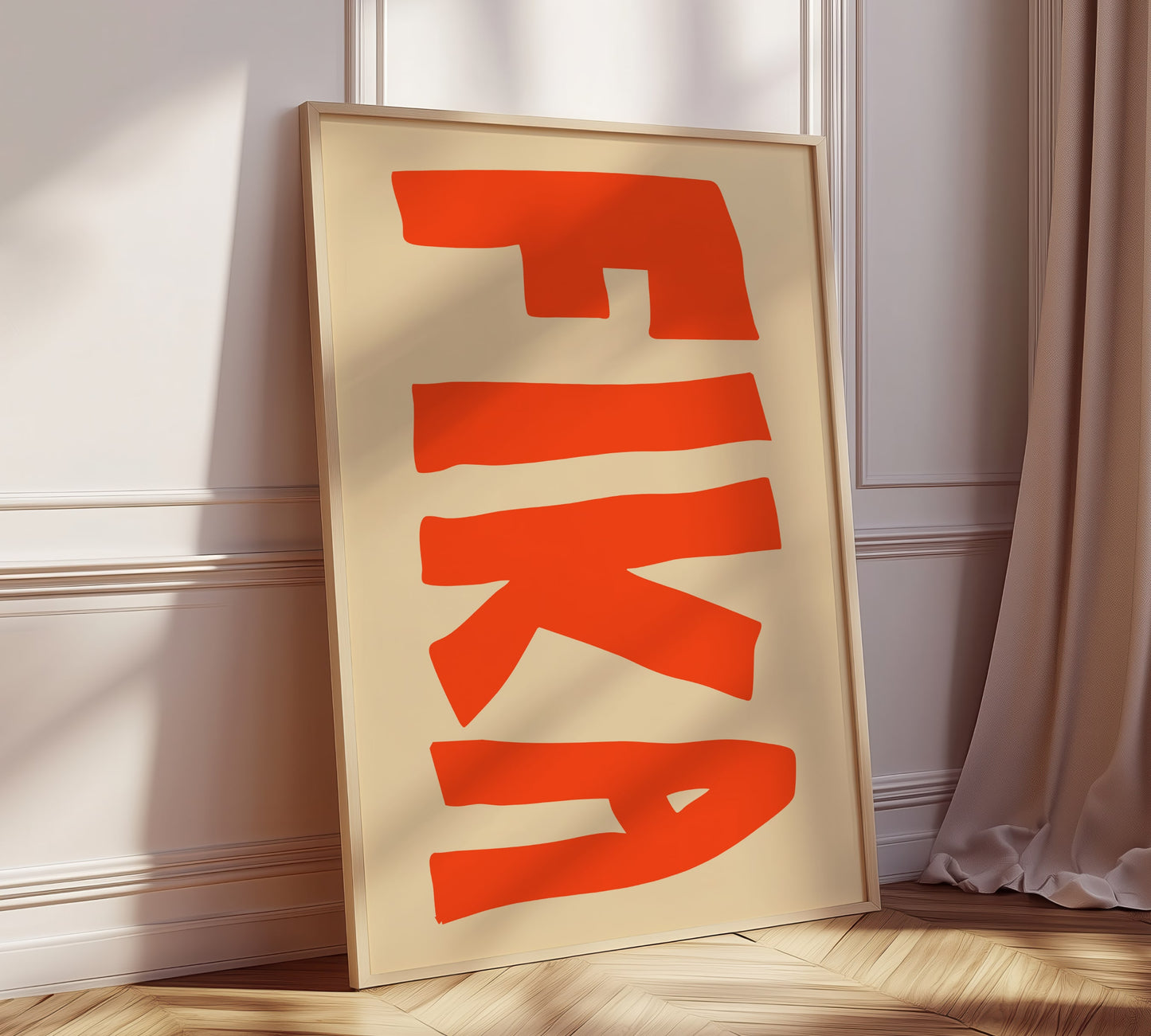 A framed picture leaning against a modern kitchen wall, on it written in big bold orange letters is the Swedish word "FIKA".