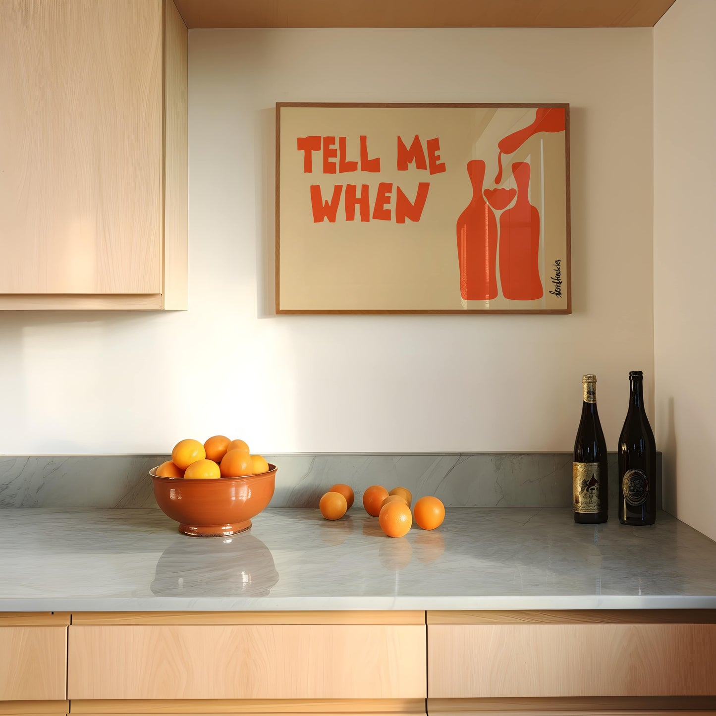 Framed wine illustration hanging above a kitchen counter with bottles and lemons