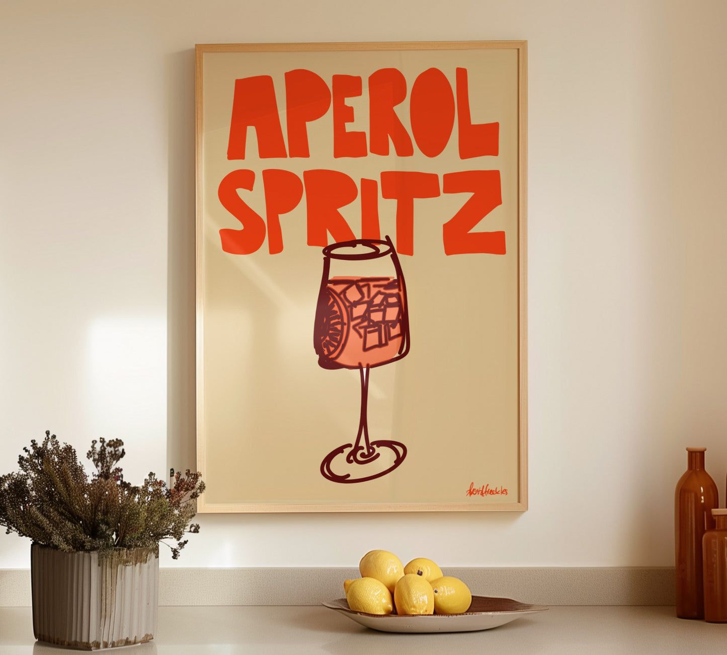 Framed Aperol Spritz illustration hanging above a kitchen counter with bottles and lemons