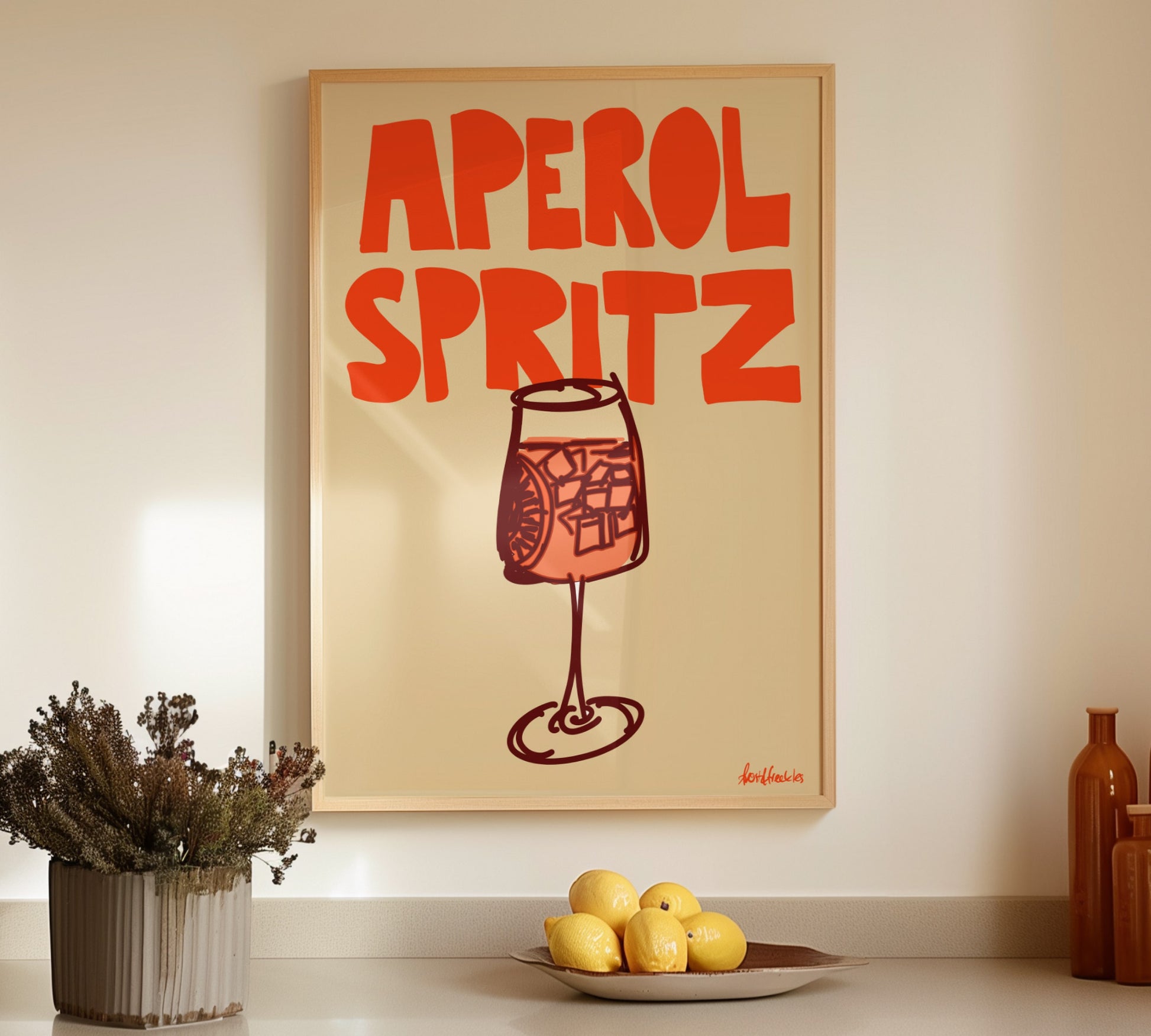 Framed Aperol Spritz illustration hanging above a kitchen counter with bottles and lemons