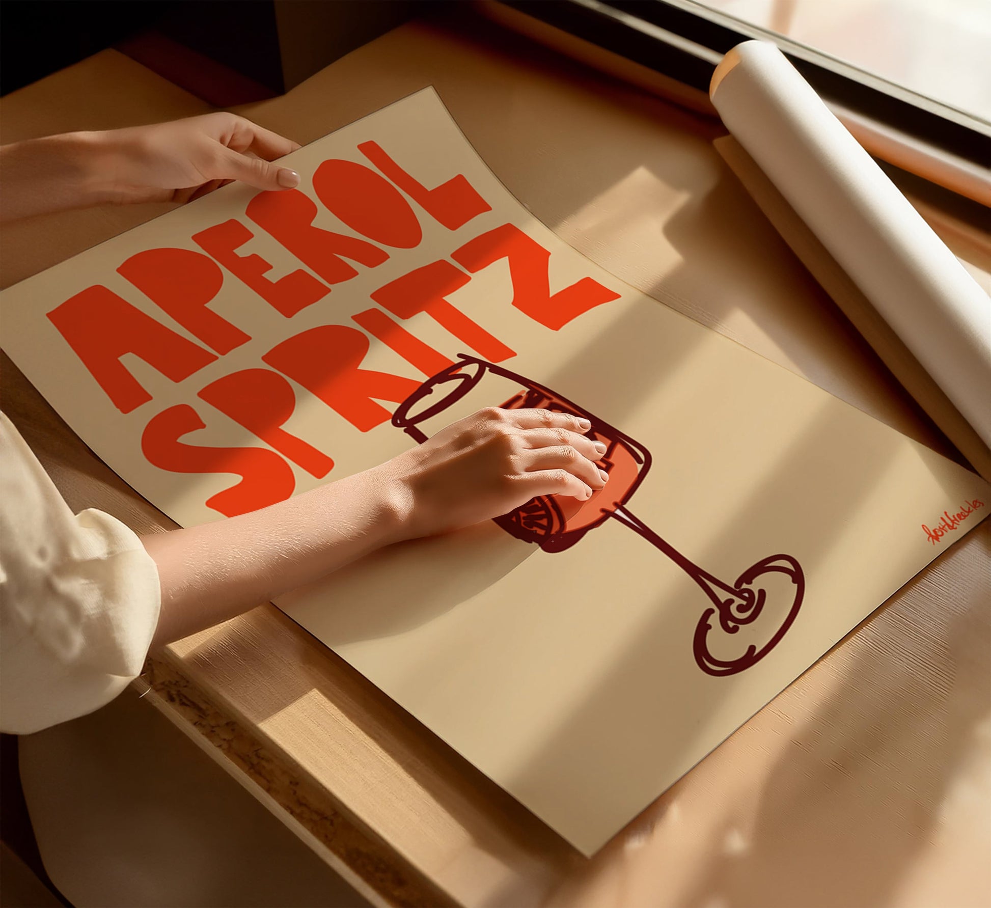 Aperol Spritz cocktail poster flat lay on beige background with woman's hands on top
