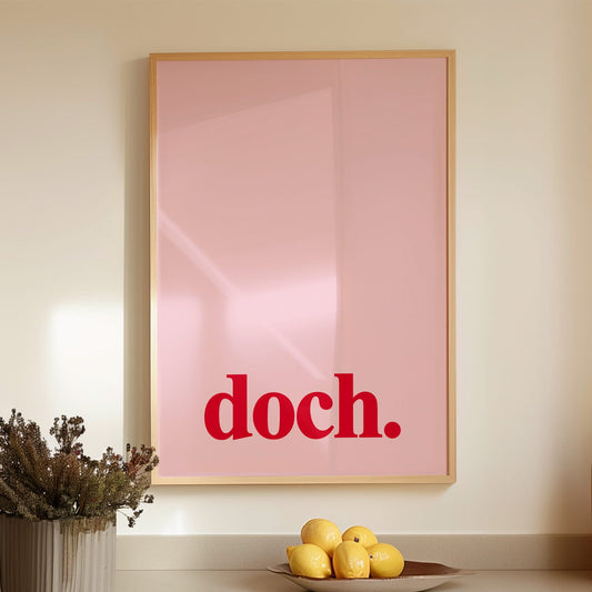 Gerahmtes Poster mit dem Wort "Doch" in roter Schrift auf pinkem Hintergrund, hängend in moderner Küchenzeile.