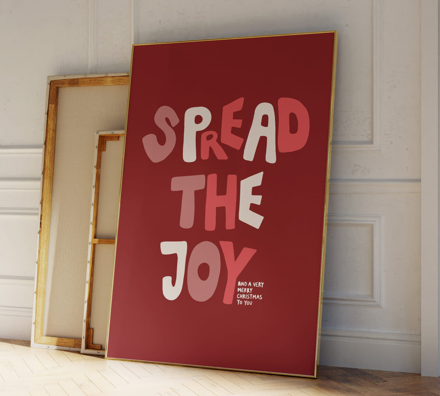 Gerahmtes Weihnachts-Poster Spread the Joy in einem Holzrahmen über einem dekorierten Kamin mit Lichterkette.