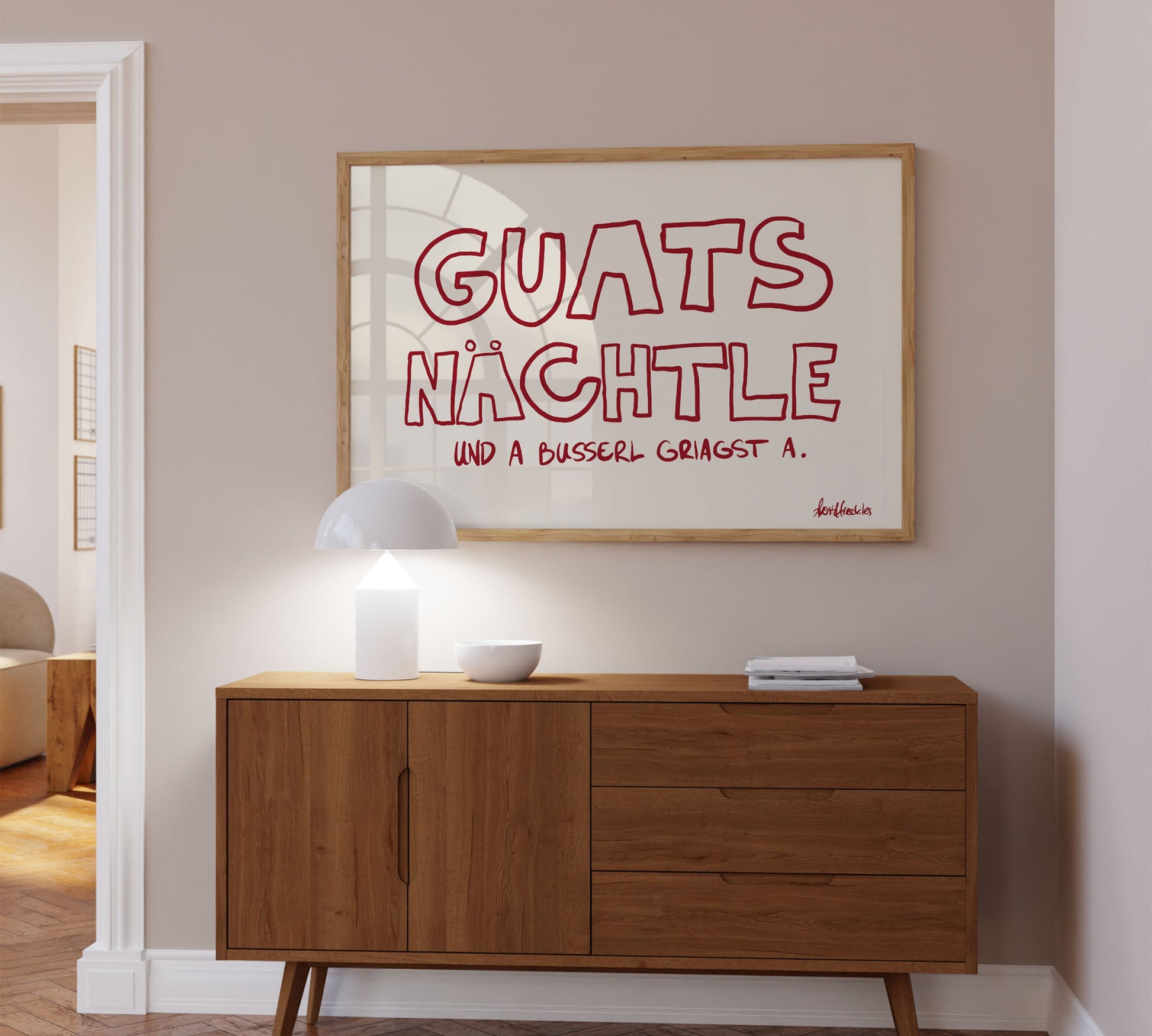 A bold red framed picture hanging above a sideboard, Danish minimalist design reading "Guats Nächtle" – a regional German goodnight phrase.