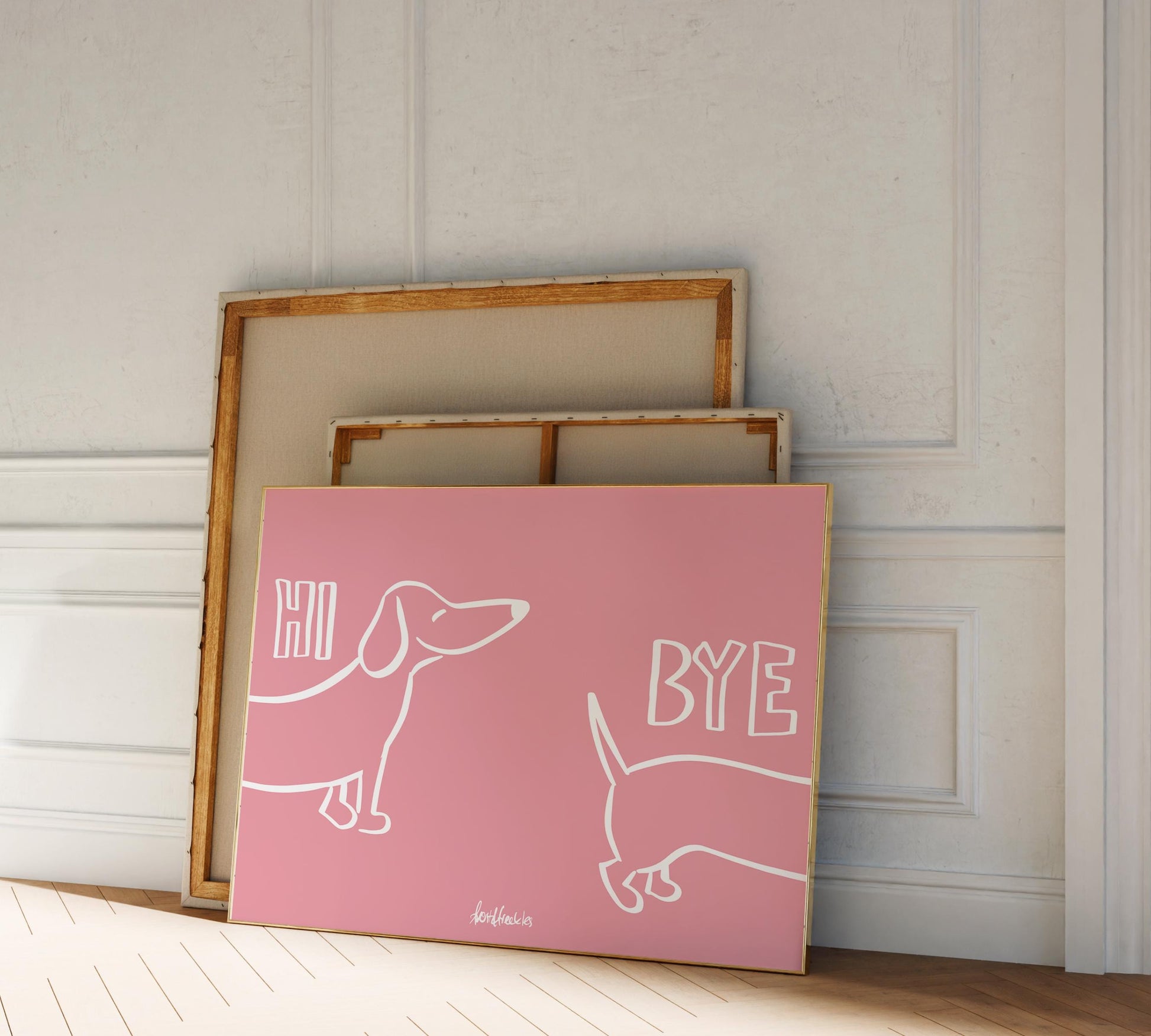 A framed picture leaning against a hallway wall, pink background and white letters reading "Hi Bye", showing a cute Dachshund illustration.
