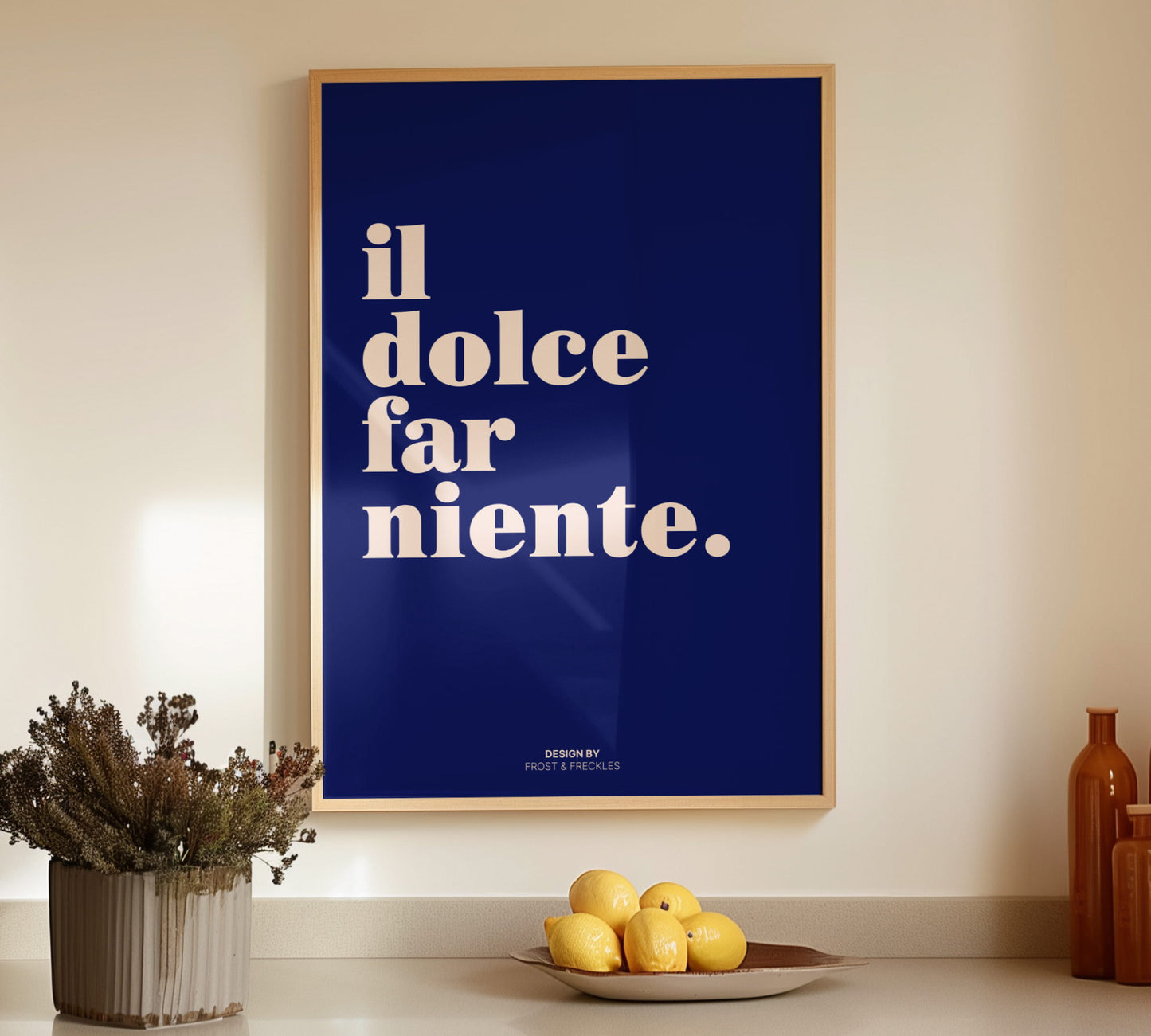 Italian wall art print il dolce far niente in a light wooden frame styled on a kitchen counter next to fresh lemons.