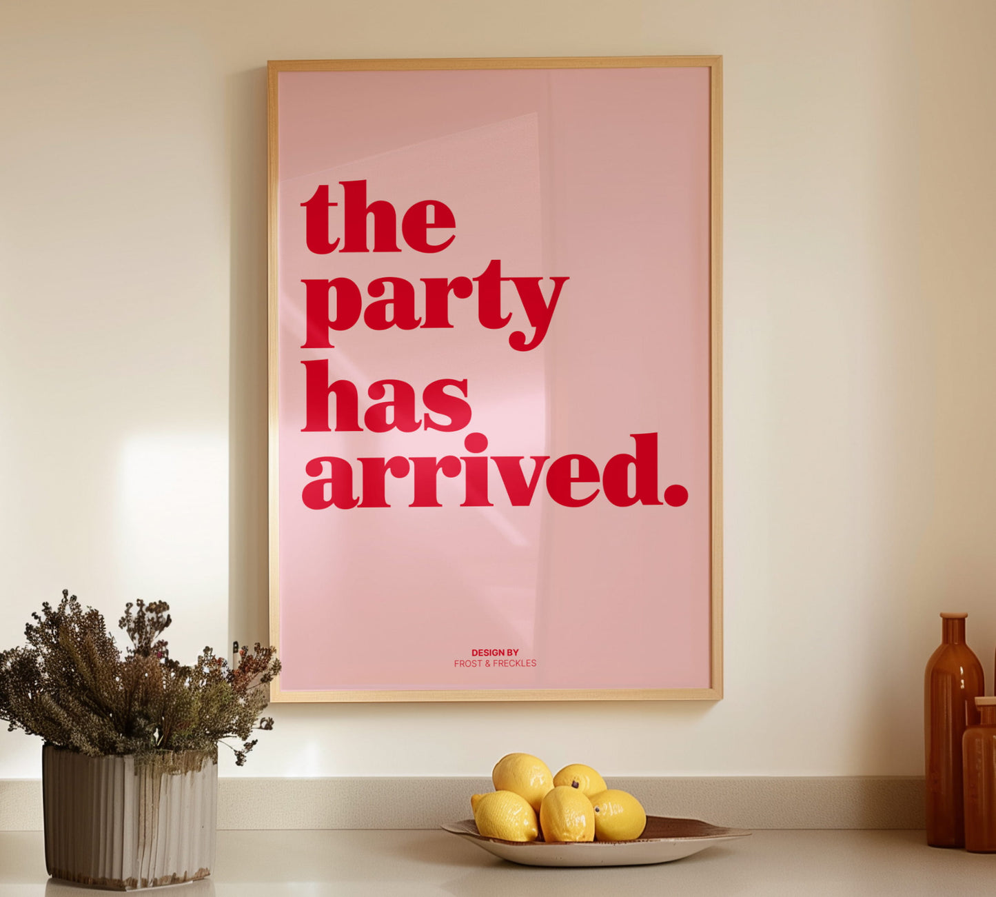 Gerahmtes Wandbild "The party has arrived" im skandinavischen Holzrahmen auf einer Küchenzeile neben gelben Zitronen platziert.