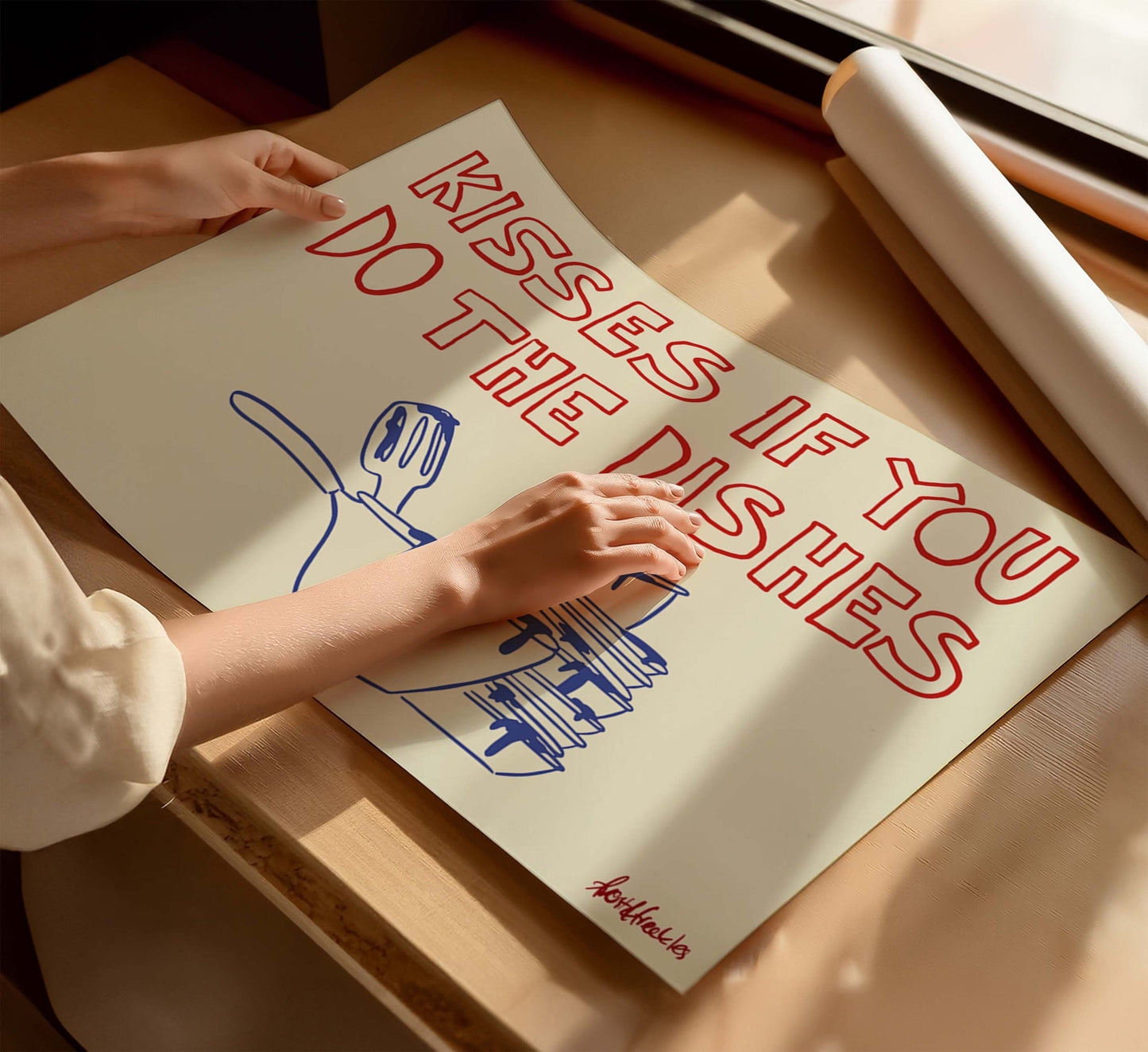 Closeup of minimalist typography art reading "Kisses If You Do The Dishes" in a bright, Scandinavian-style kitchen