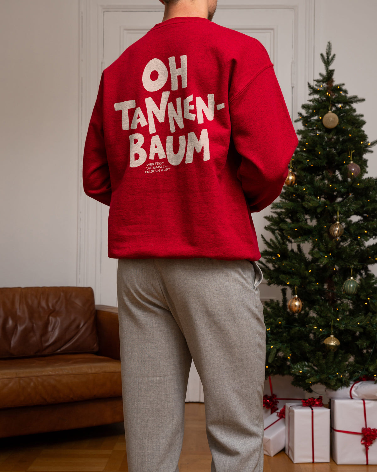 Roter Weihnachtspulli mit dem lustigen Aufdruck "Oh Tannenbaum – Wer fegt die ganzen Nadeln auf?"