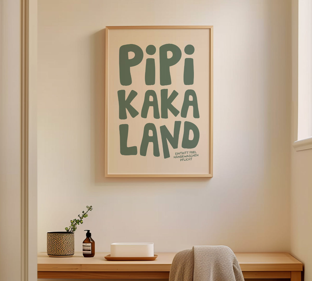 Gerahmtes Klo-Wandbild „Pipi Kaka Land“ in einem hellen Holzrahmen an einer hellen Wand im Gästebad.