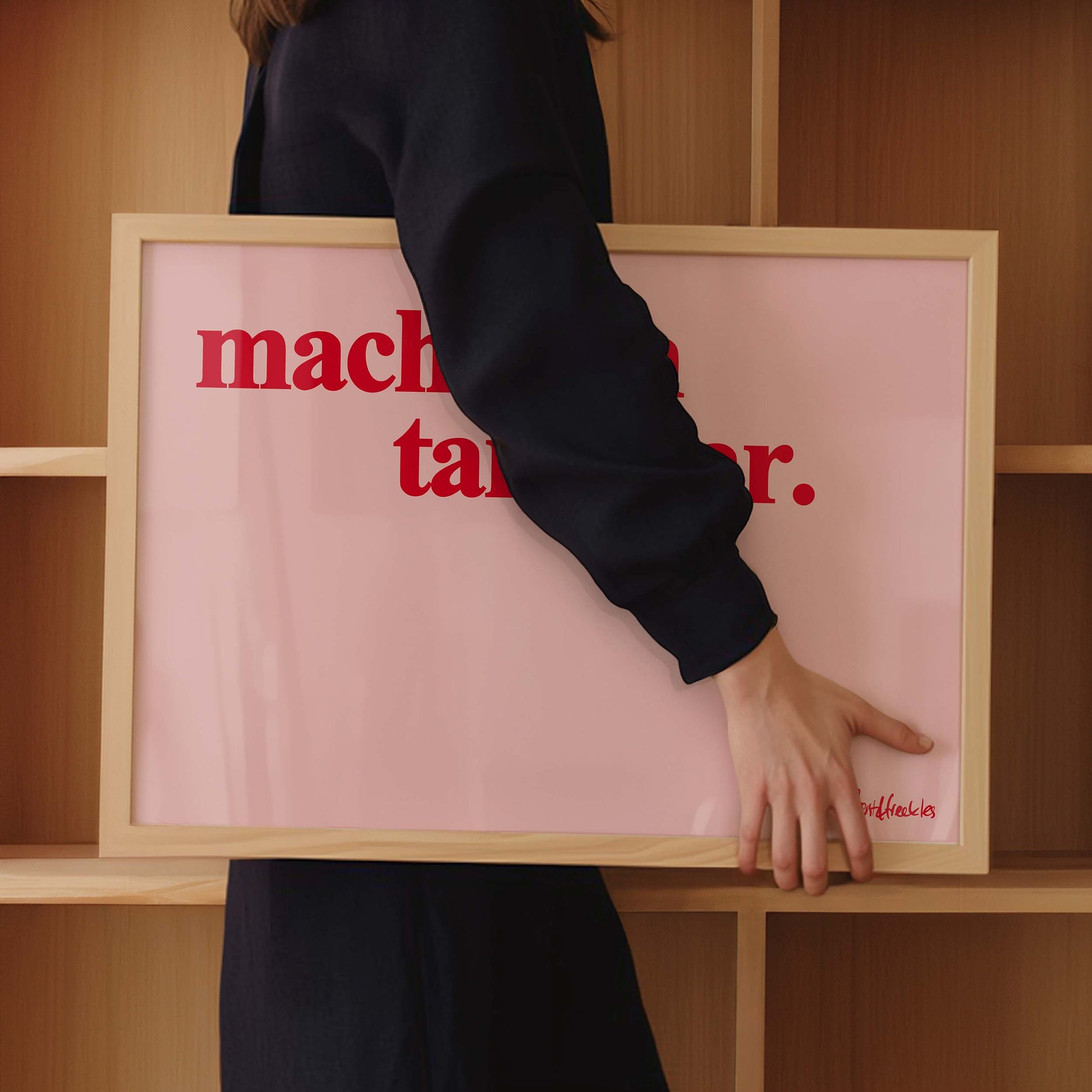 Eine Frau hält einen Holzbilderrahmen unter dem Arm, auf dem Poster ist in roter Schrift der Spruch "mach dich tanzklar" zu lesen.