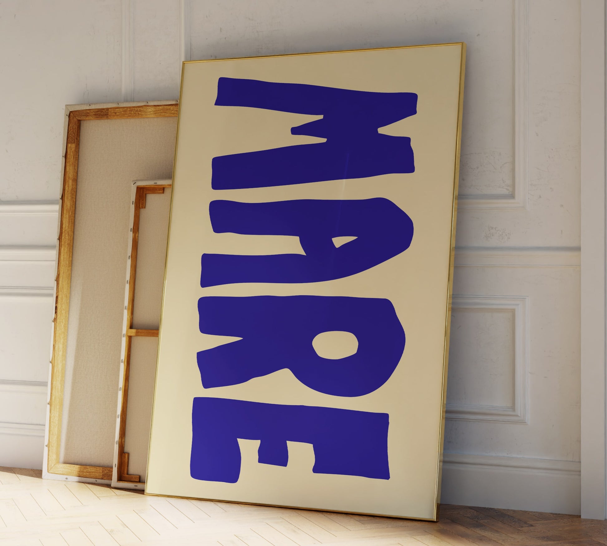 Two frames leaning against a modern living room wall, in big blue letters the Italian word "MARE" for ocean is printed on it.