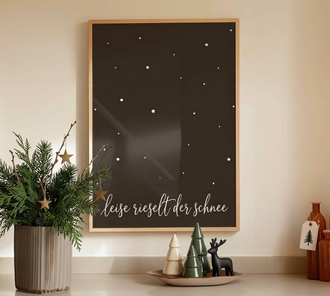 Gerahmtes Weihnachts-Poster „Leise rieselt der Schnee“ in einem hellen Holzrahmen über einem dekorierten Sideboard.