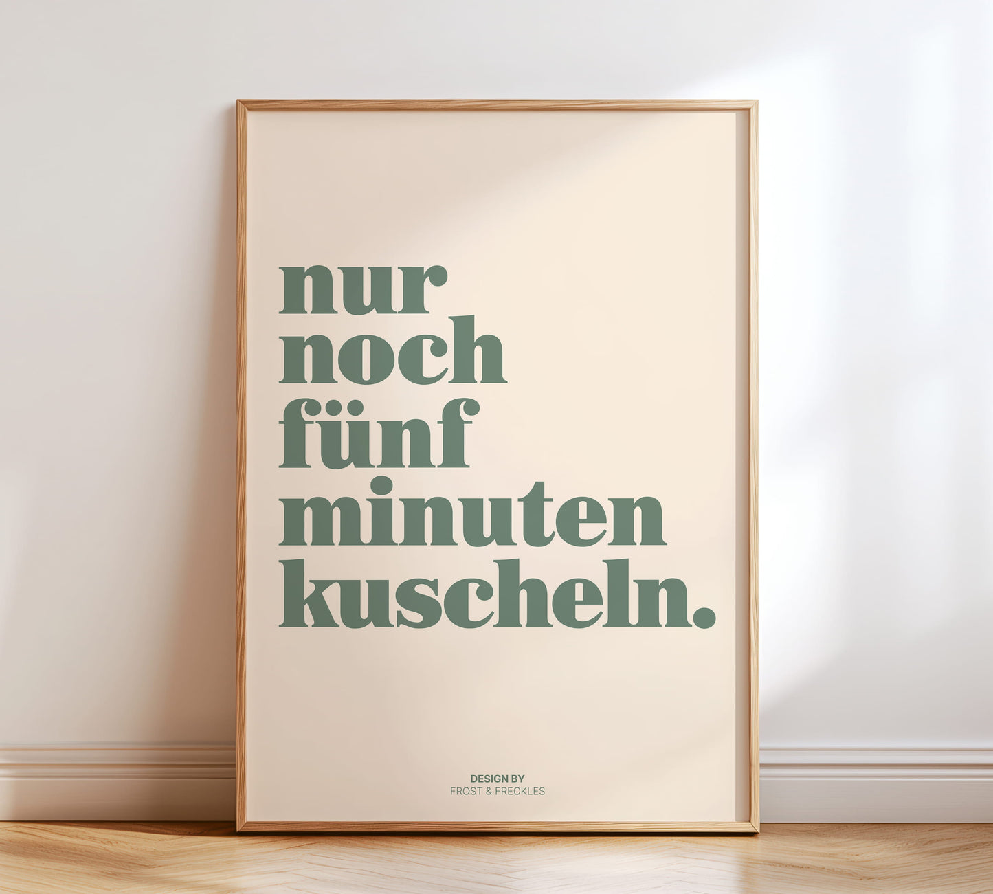 Minimalistisches Typografie-Poster mit dem Text "Nur noch 5 Minuten kuscheln" in Salbeigrün auf Nachttisch.  