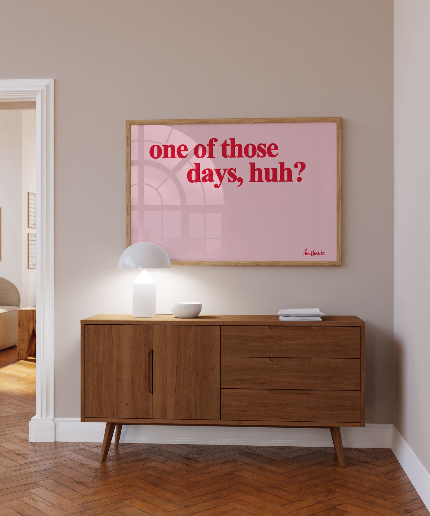 A bold bright pink and red framed picture hanging above a sideboard, Danish minimalist design reading "one of those days".