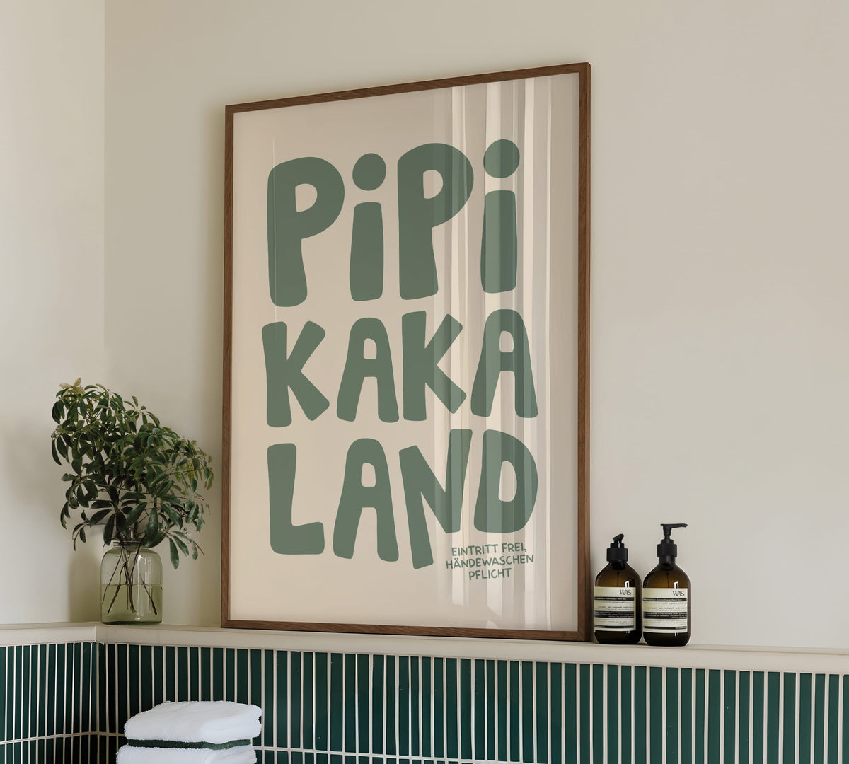 Gerahmtes Bad-Wandbild „Pipi Kaka Land“ in einem dunklen Holzrahmen an einer hellen Wand im Badezimmer.