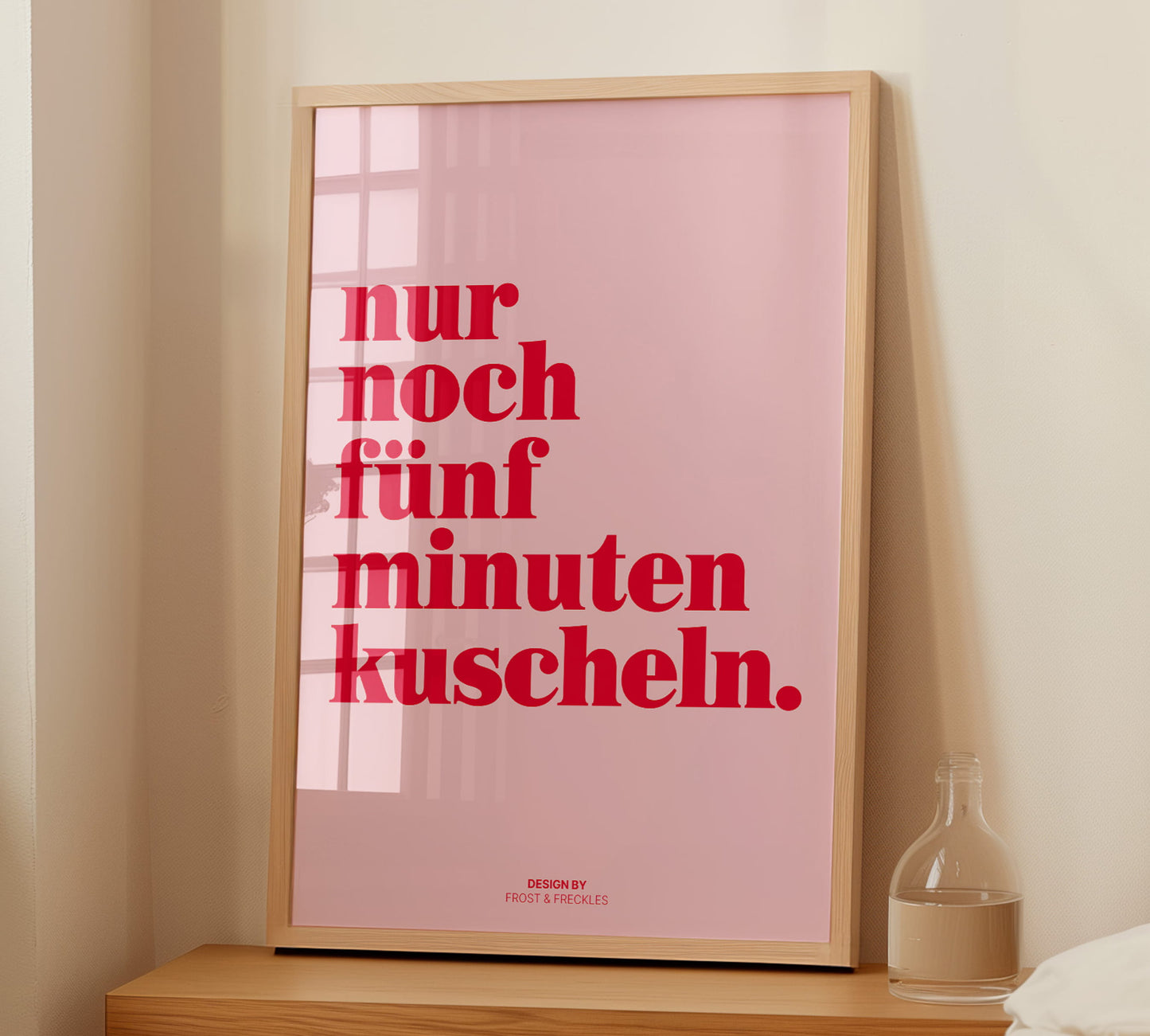 Ein gerahmtes 5-Minuten-Kuscheln Poster auf einem Nachttisch kombiniert mit minimalistischer Deko.