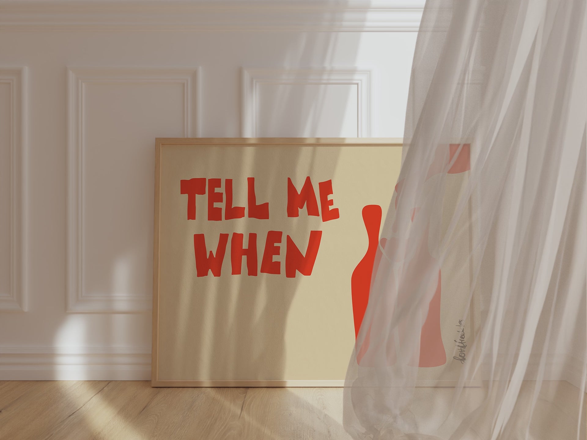 A framed picture leaning against a kitchen wall, beige background and bold orange letters reading "Tell Me When", while wind is blowing window curtain inside.