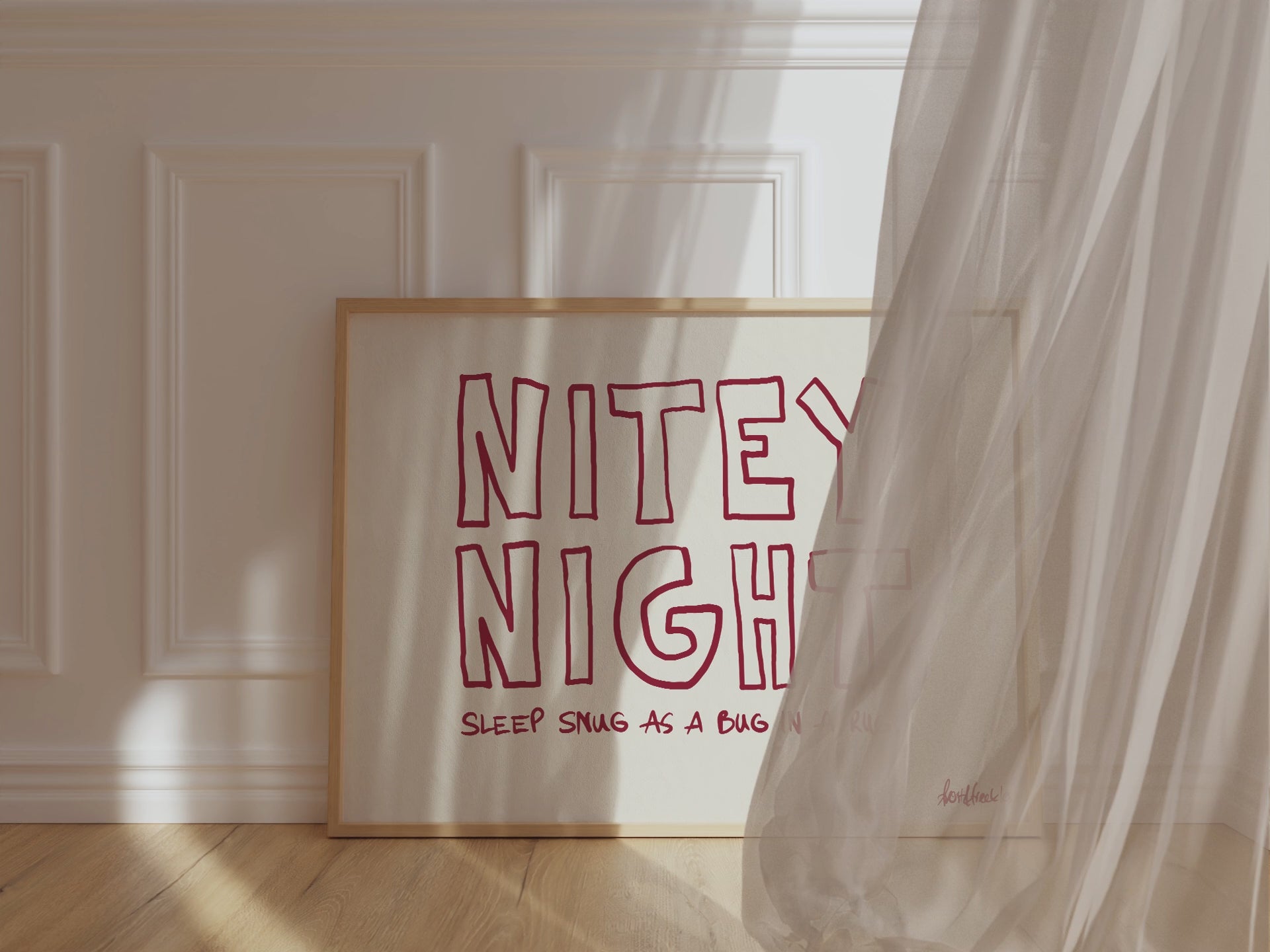 A framed picture leaning against a bedroom wall, beige background and bold red letters reading "Nitey Night", while wind is blowing window curtain inside.