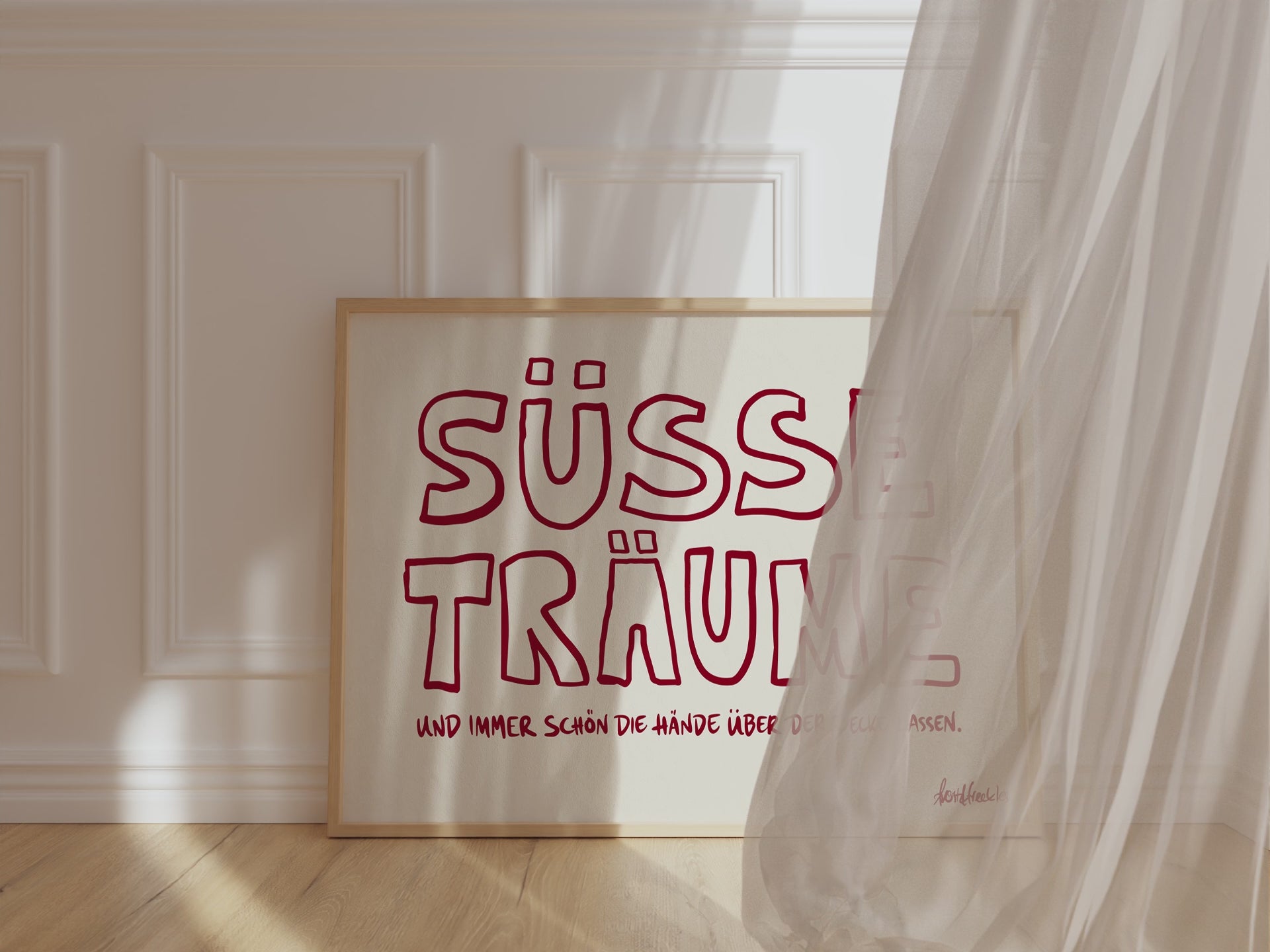 Ein Bilderrahmen lehnt gegen eine Schlafzimmer Wand, im horizontalen Format ist der Text "Süße Träume" in moderner Typografie zu lesen.
