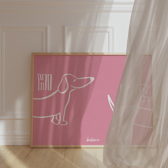 A framed picture leaning against a hallway wall, pink background and bold white letters reading "Hi Bye" with cute Dachshund illustration in center.
