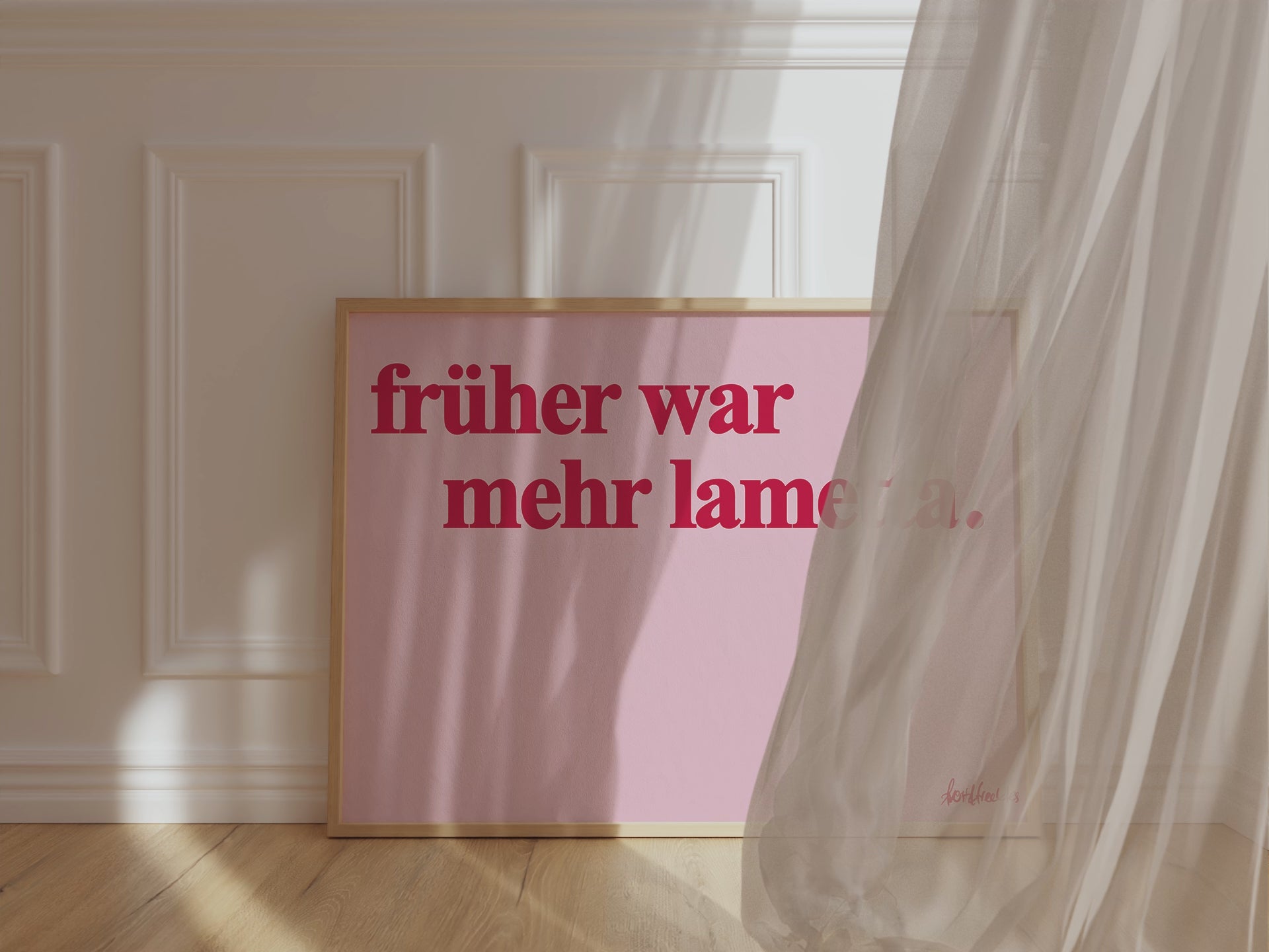Ein gerahmtes Bild, das gegen ein Wand lehnt, zeigt den deutschen Text "Früher war mehr Lametta", ein Zitat von Loriot, in roter Schrift auf pinkem Hintergrund. Ein Vorhang weht vor den Rahmen durch Wind.