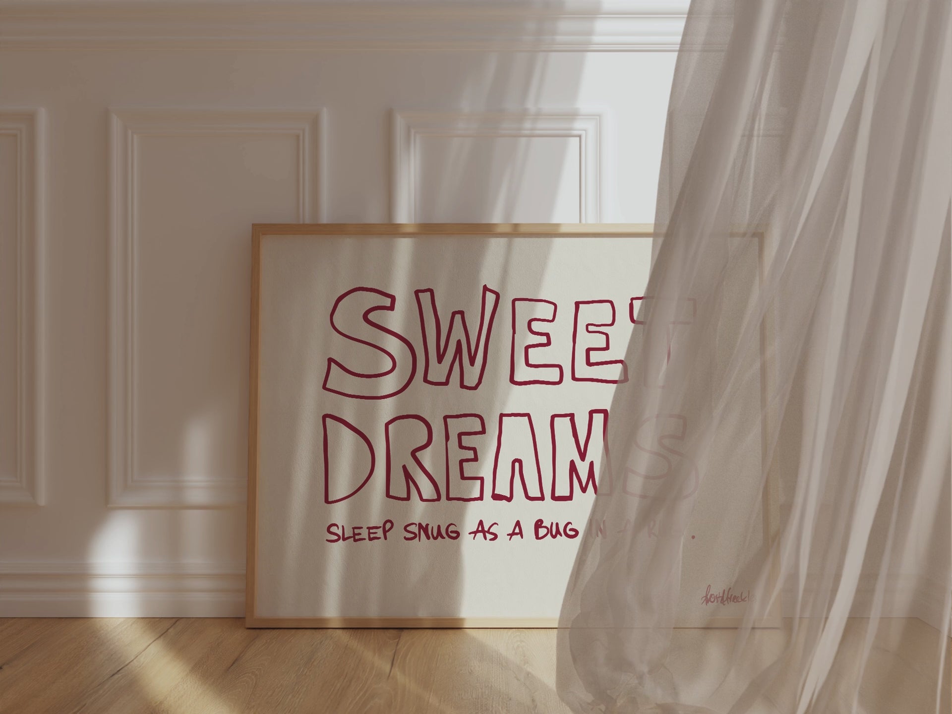 A framed picture leaning against a bedroom wall, beige background and bold red letters reading "Sweet Dreams", while wind is blowing window curtain inside.