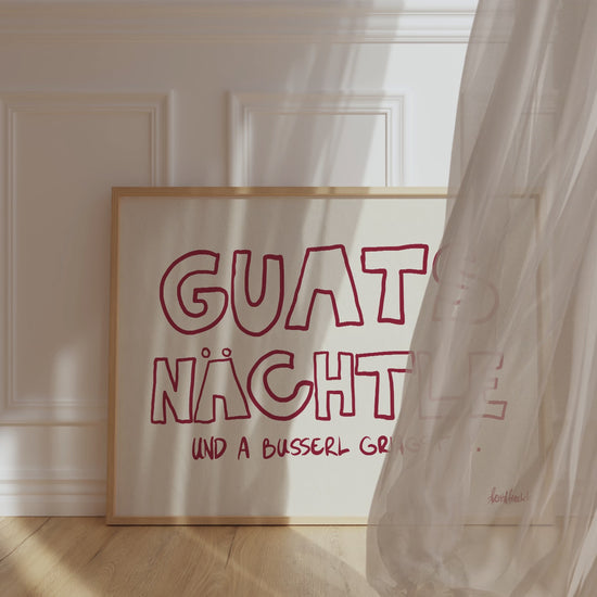 Gerahmtes Poster in horizontalem Format zeigt den Spruch "Guats Nächtle" bzw. "Gute Nacht" in roter Schrift auf pinkem Hintergrund.
