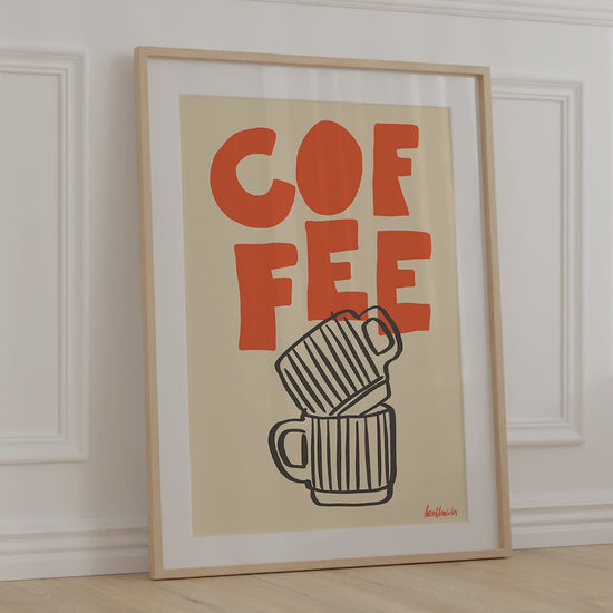 A framed picture leaning against a bedroom wall, beige background and bold orange letters reading "COFFEE"