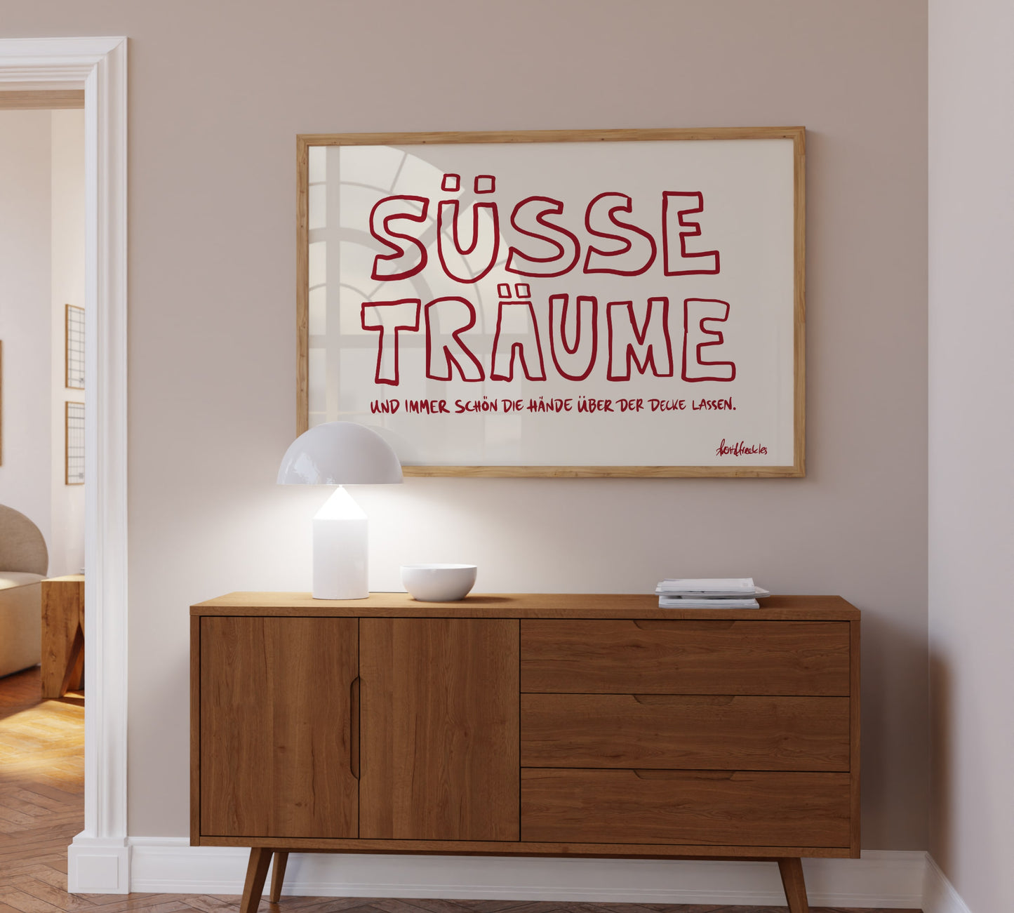 Ein gerahmtes Bild mit dem Schriftzug "Süße Träume" hängt über einer Kommode im Kinderzimmer.