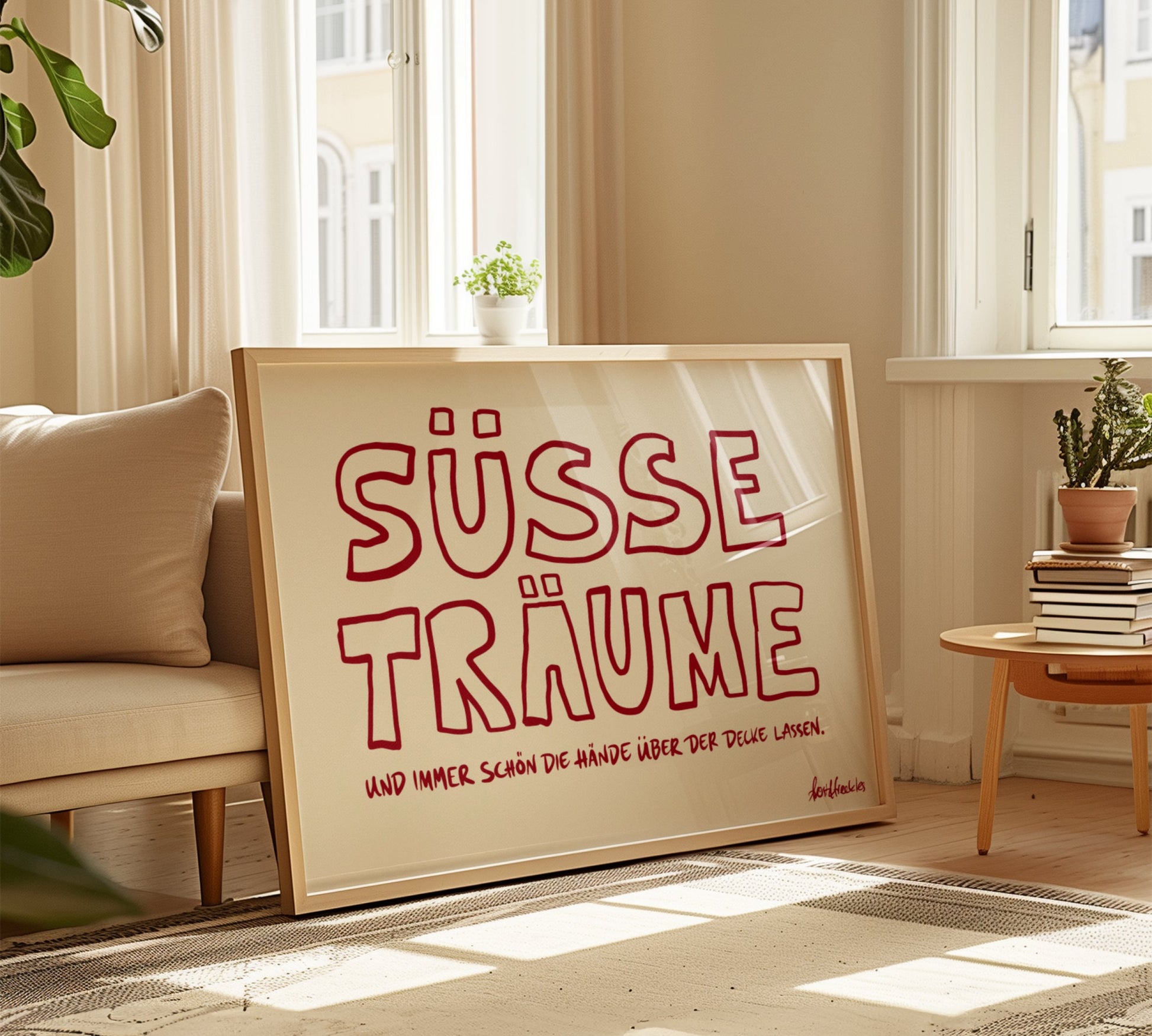 Ein gerahmtes Bild lehnt gegen eine Couch, beiger Hintergrund mit rotem Text, der "Süsse Träume" liest.