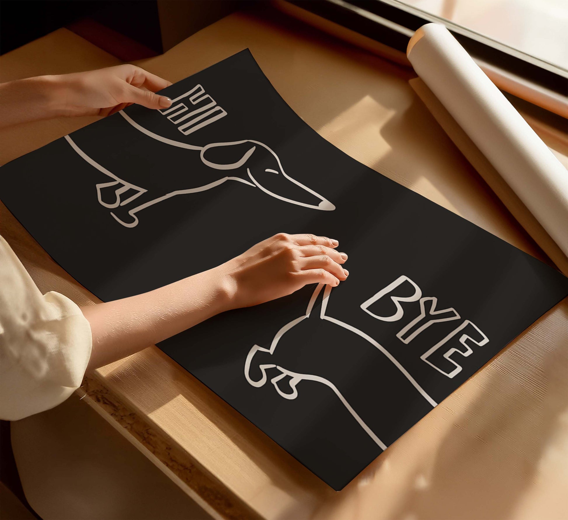 A woman holding a black poster with the words "hi bye" and a sausage dog illustration, on a wooden table near a window with sunlight. 
