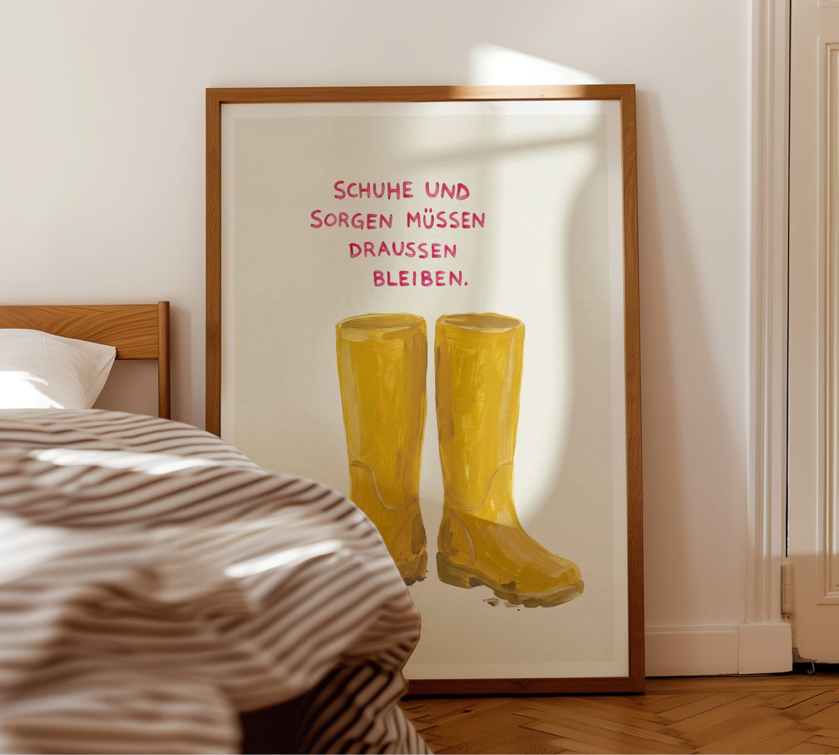 Gerahmtes Flur-Poster mit Gummistiefel-Motiv in einem hellen Holzrahmen an der Wand im Eingangsbereich.