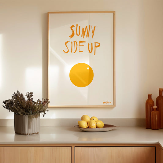 Minimalist sunny side up egg poster print with white background and orange / yellow egg illustration, framed in modern kitchen setting