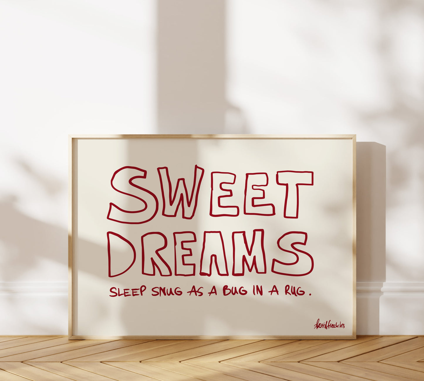 A picture frame leaning against a bedroom wall, bold red lettering reading "Sweet Dreams".
