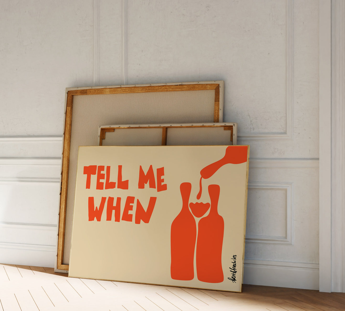 Framed wine poster reading "Tell Me When" as part of a gallery wall with neutral decor in hallway