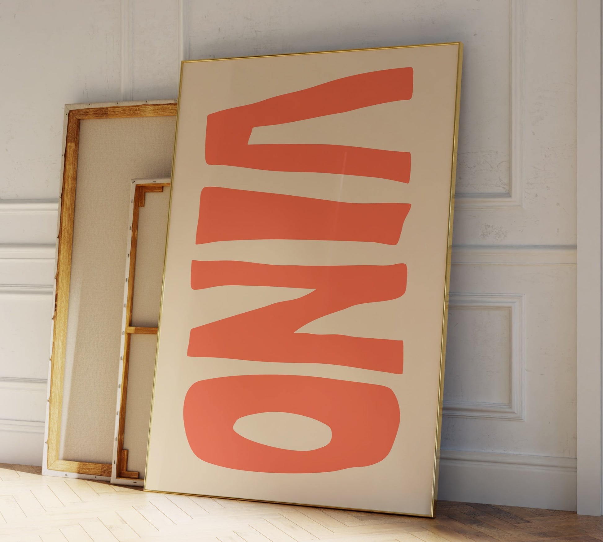 Two frames leaning against a modern living room wall, in big orange letters the Italian word "VINO" for wine is printed on it.
